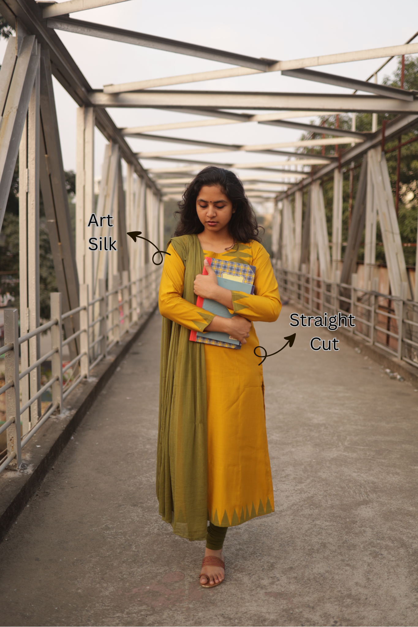 Woman wearing a yellow and green outfit on a bridge, with text indicating fabric type and cut.