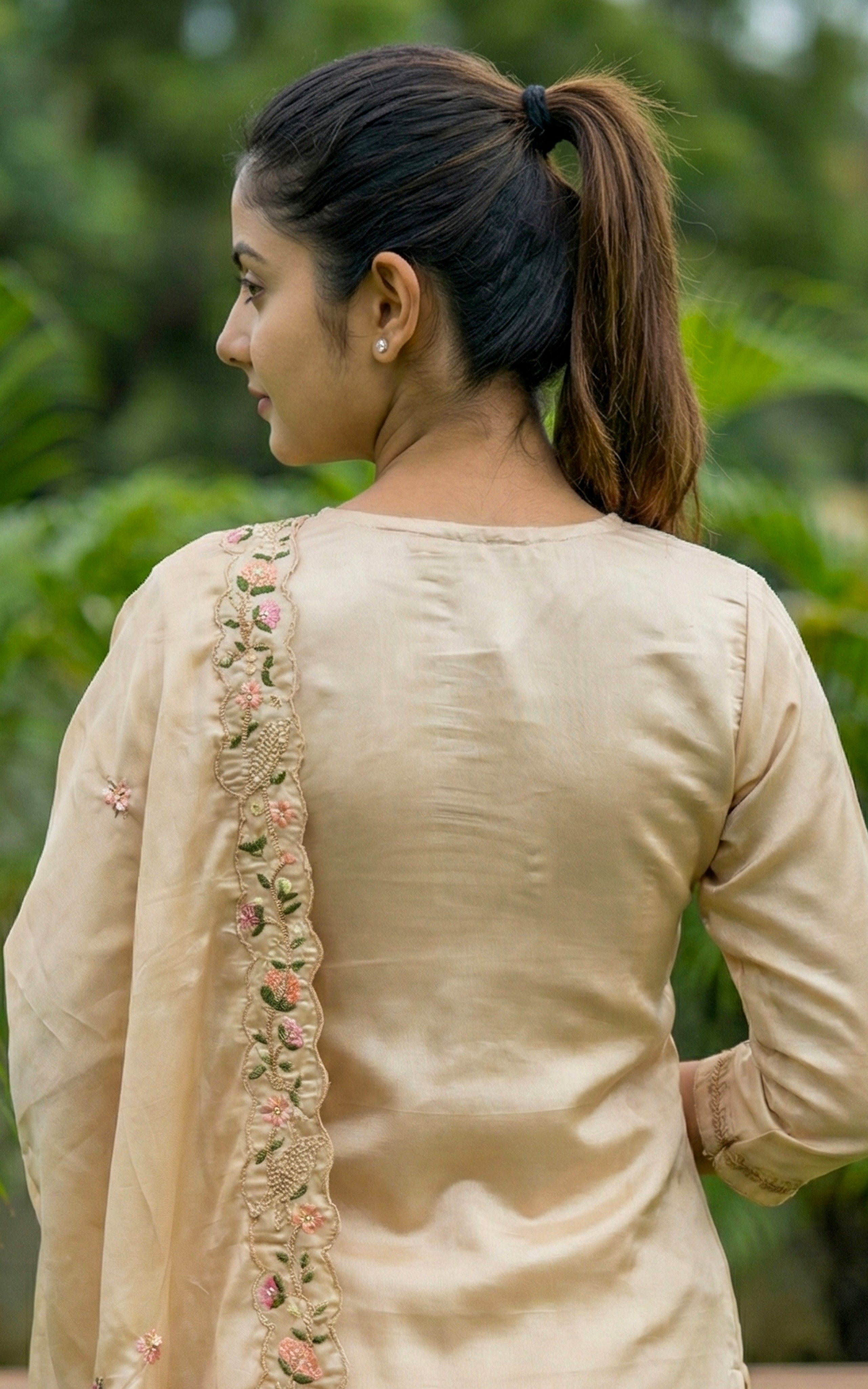 Woman wearing a beige traditional outfit with floral embroidery