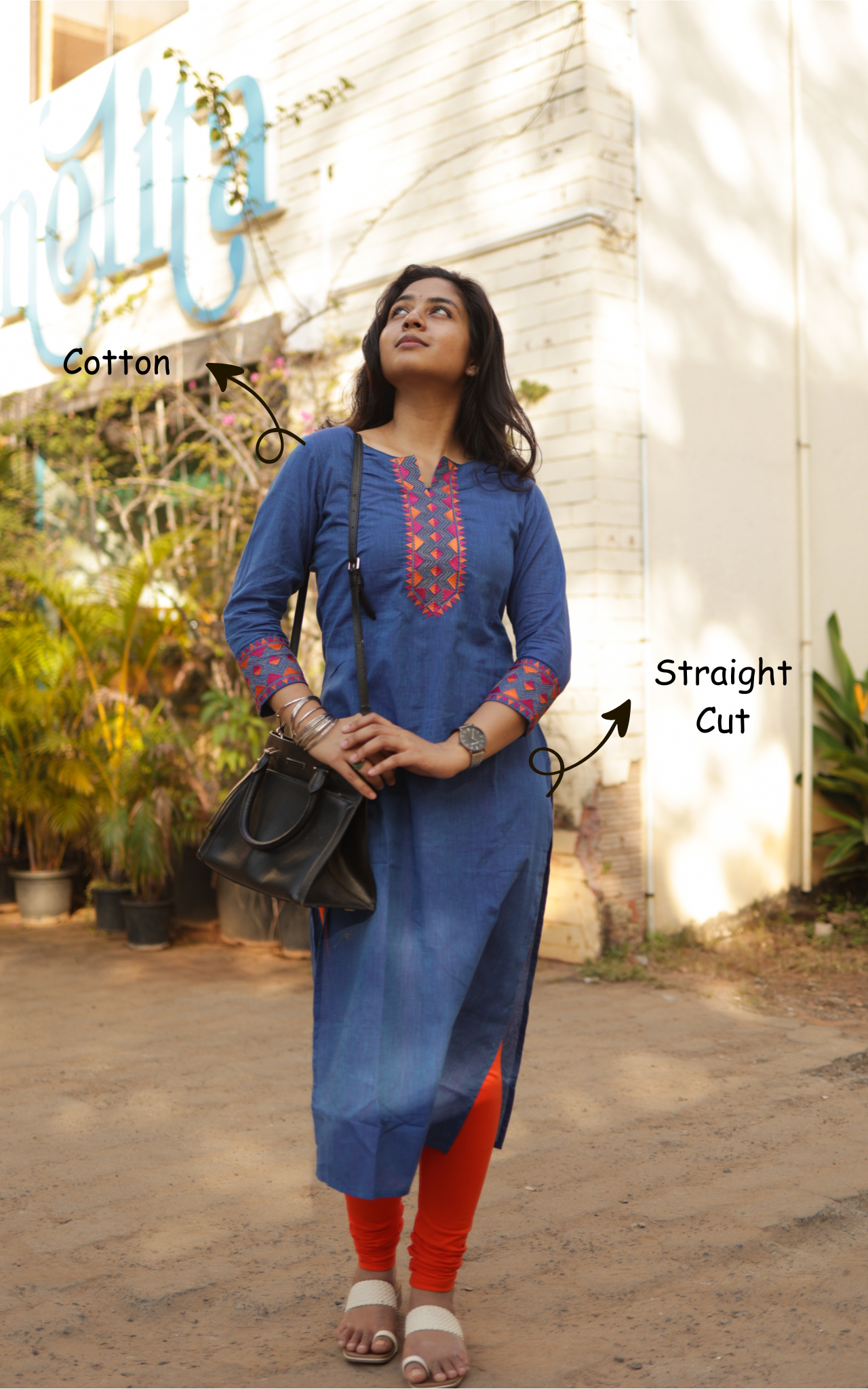 Woman wearing a blue kurta with red embroidery in an outdoor setting