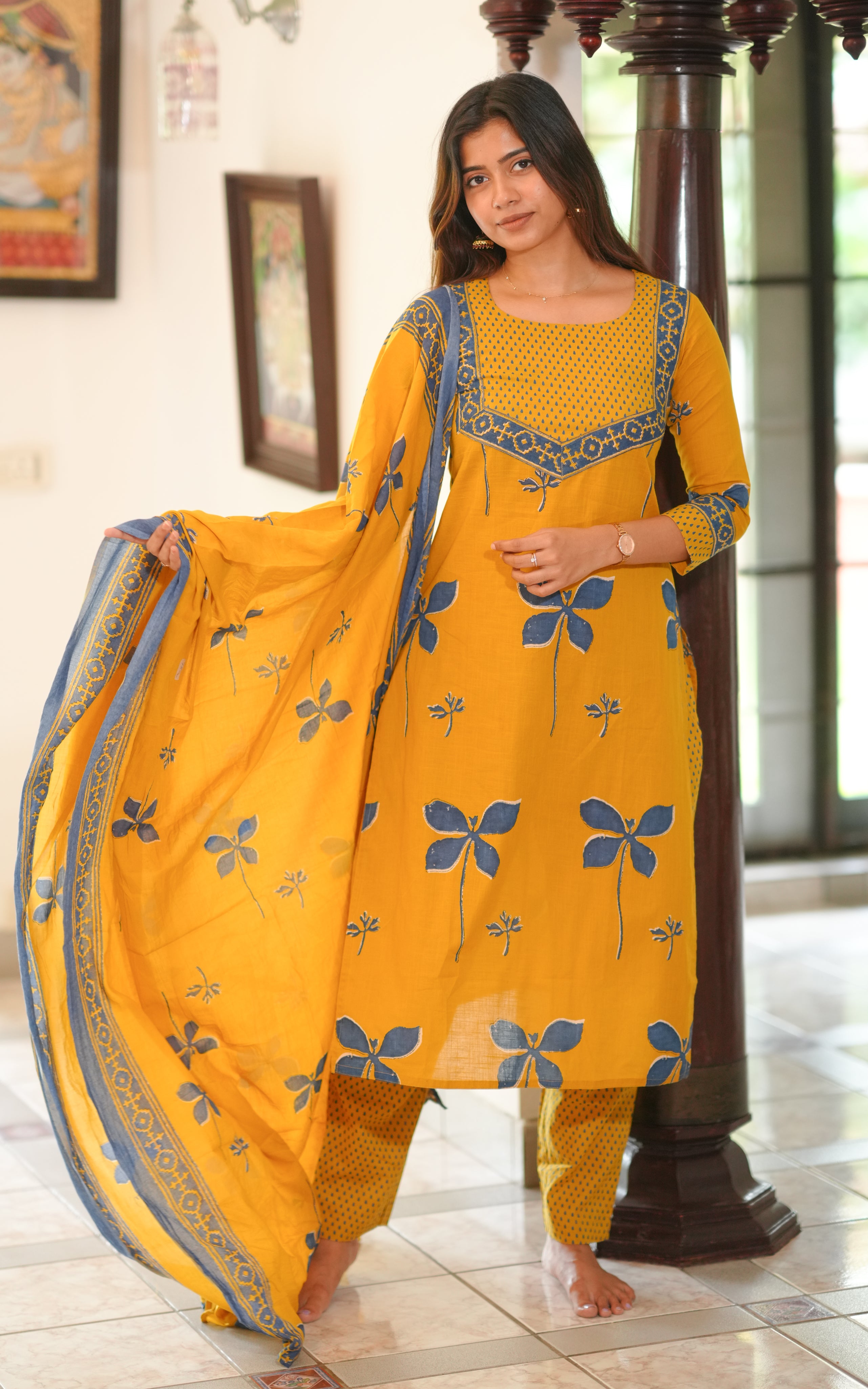 Woman wearing a mustard yellow straight cut kurti with blue floral block print.
