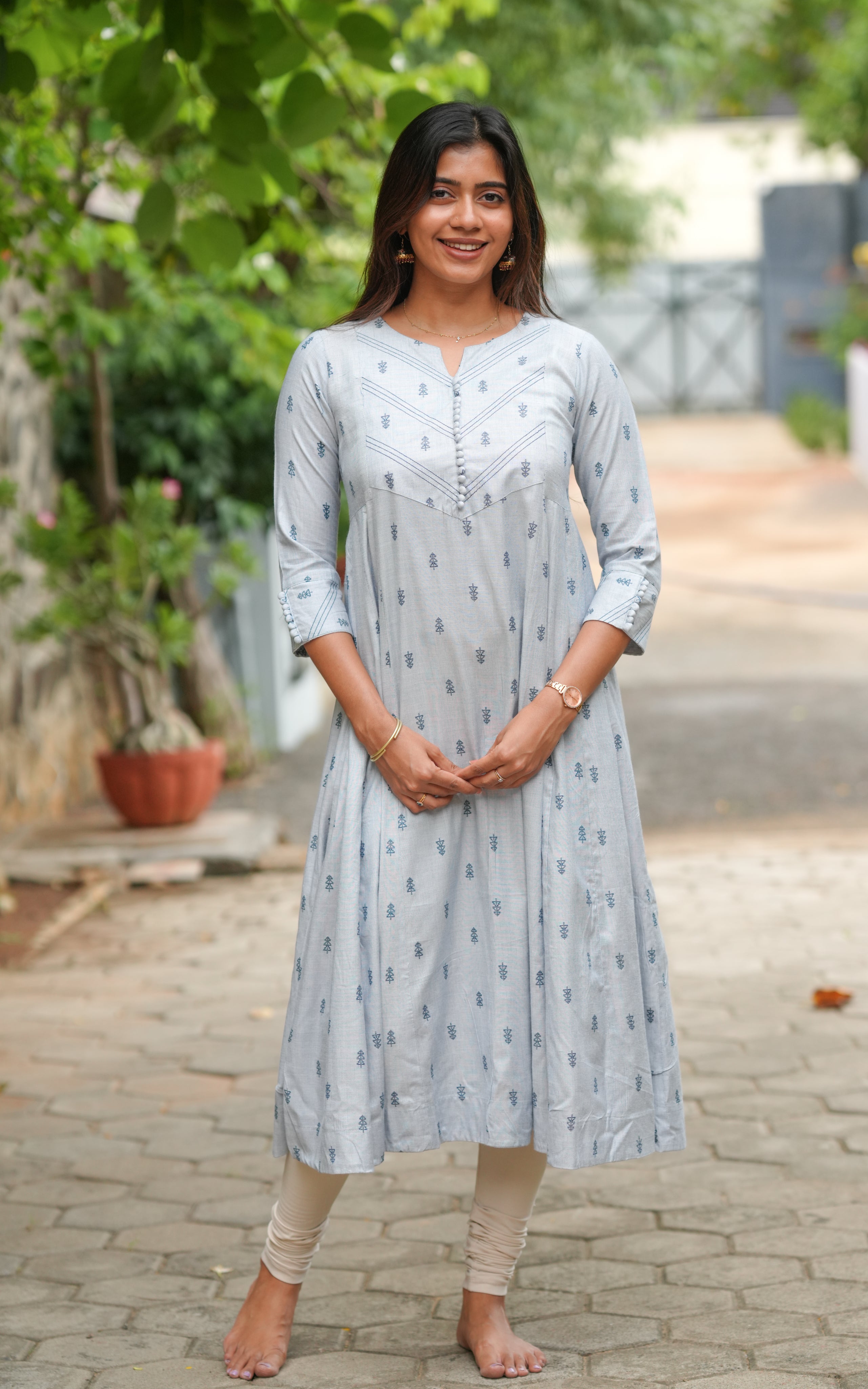 A woman is wearing a soft grey cotton kurti with delicate blue motifs all over.