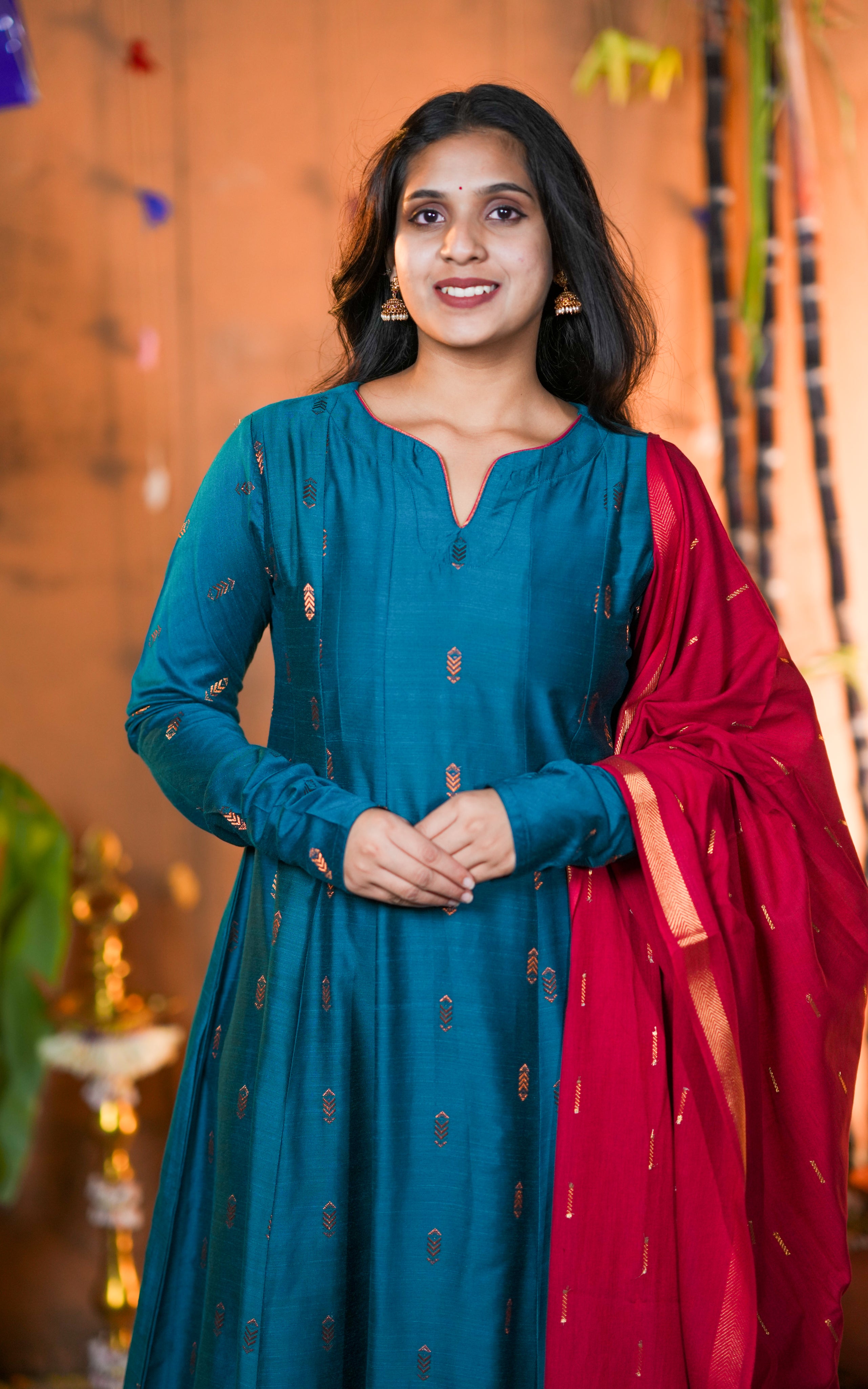 Woman in a teal dress with a red dupatta