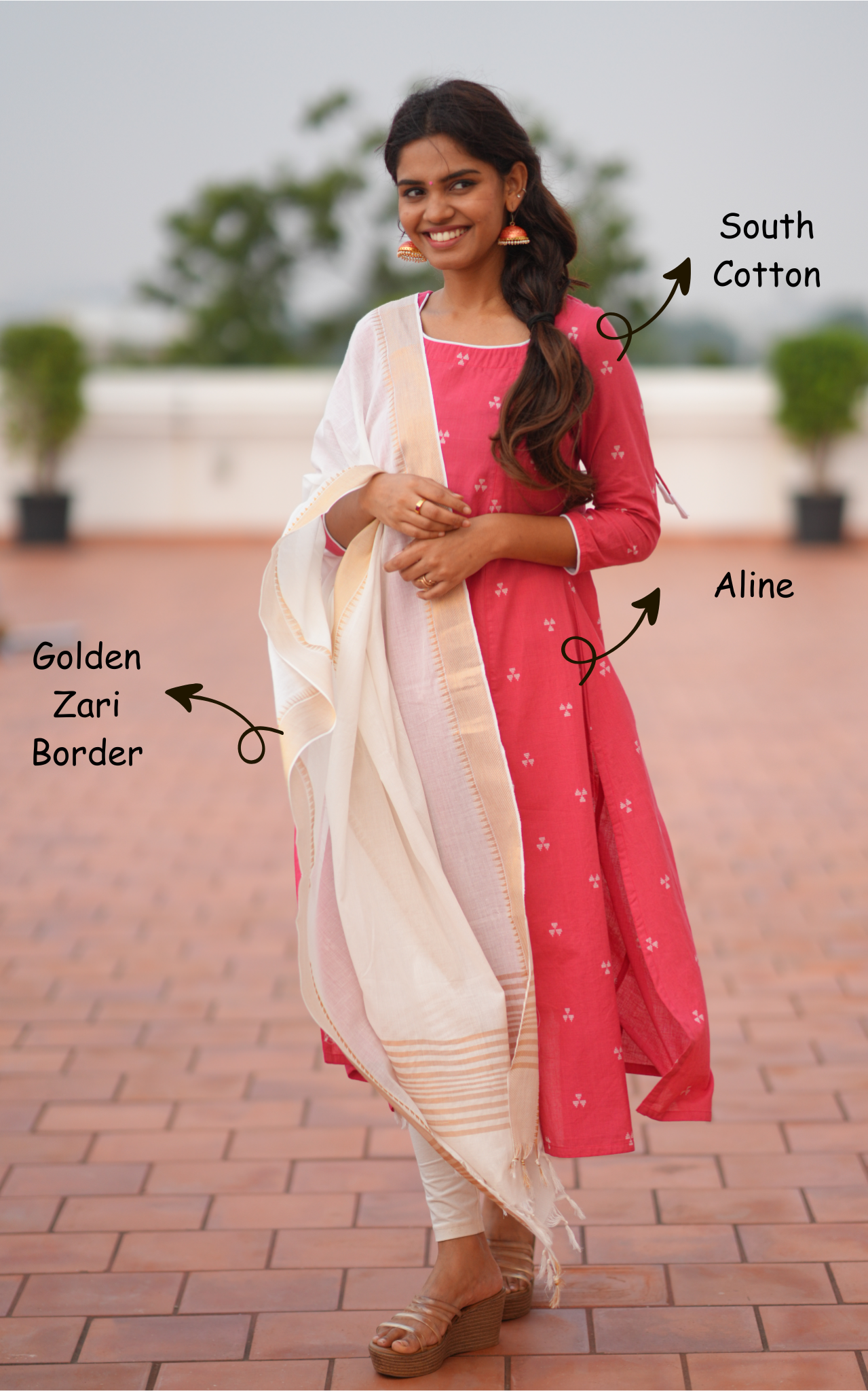 Woman wearing a pink traditional outfit with white dupatta on a brick pathway.